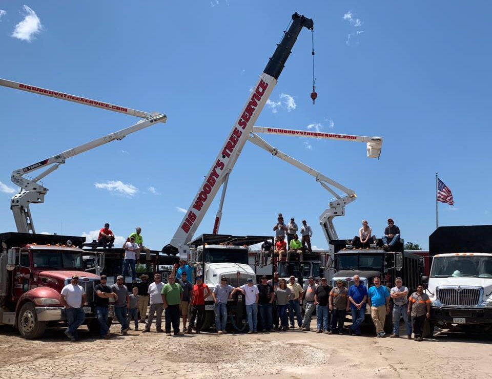The Big Woody's crew lined up in front of their trucks, bucket trucks and crane